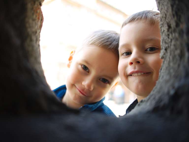 Two boys looking through a whole in the wall
